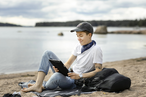 Personen läser från sin smart enhet på stranden.